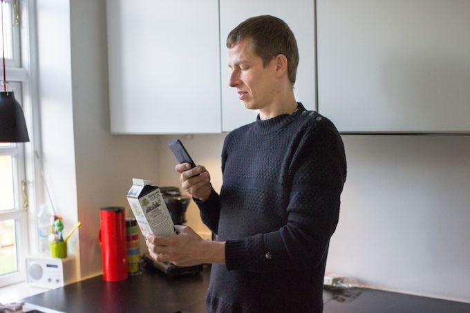 Visually impaired man video chatting to check the expiry date on a milk carton.